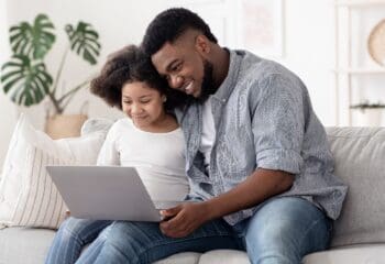 Online School Applications. African American Father And Daughter Using Laptop At Home Together, Checking Admission Status