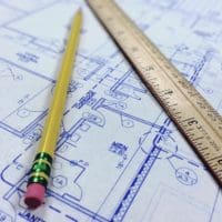 A pencil sits on top of blueprints.